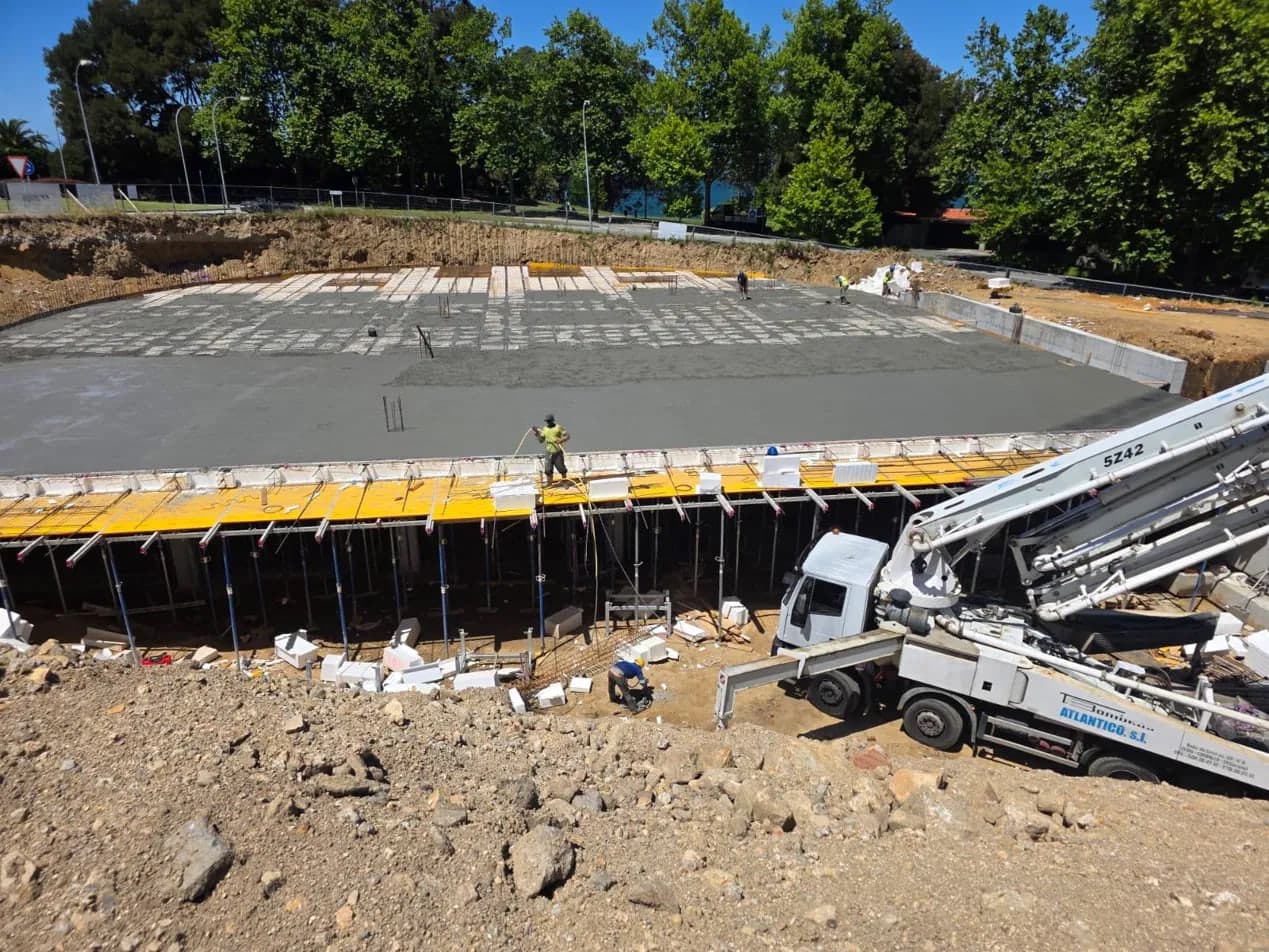 Pouring a floor slab with a concrete pump and a worker spreading the concrete