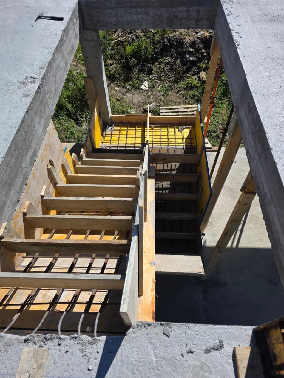 Encofrado de madera y armadura de una escalera de hormigón armado vista desde la planta superior