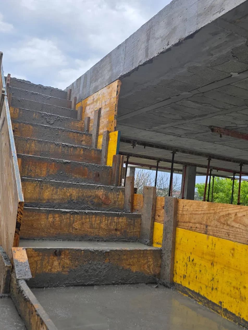 Freshly poured concrete staircase still in its formwork below a propped slab
